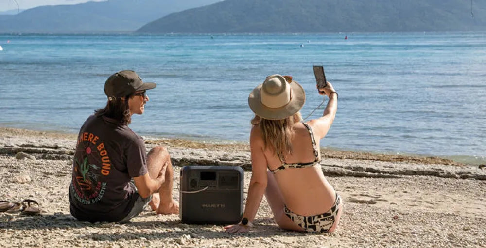 Two people enjoying the beach with a Bluetti AC180P power station and cooler